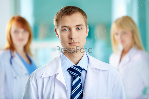 Portrait of serious clinician in white coat looking at camera