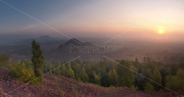 The top view landscape on valley with waste heaps in fog and rising sun