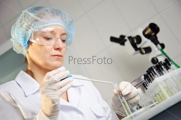 A female doctor examines a sample. Shallow depth of field. Focus on foreground, hands. Could be useful for medicine, hospital, research and development, clinical studies, forensics, science etc