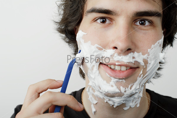 Красивый юноша бреется