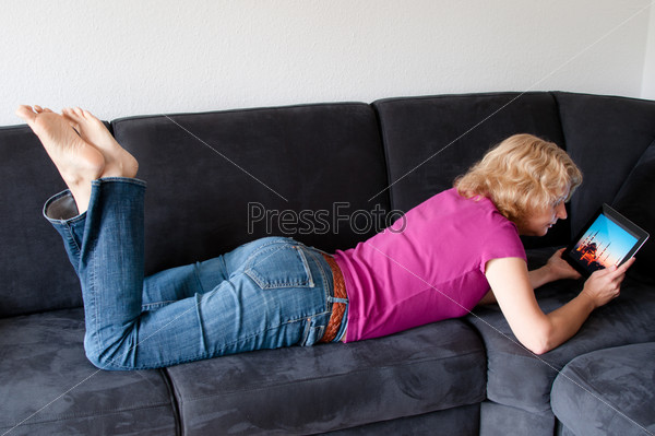 Женщина с планшетным компьютером на диване