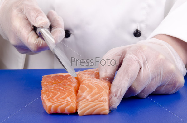 Female chef cuts salmon fillets