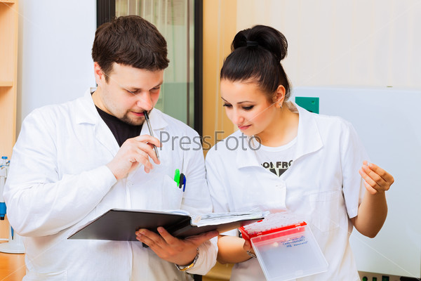 Two scientists with lab journal discussing results of experiment