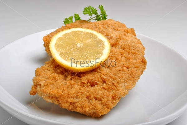 breaded fish steak with organic herbs on a plate