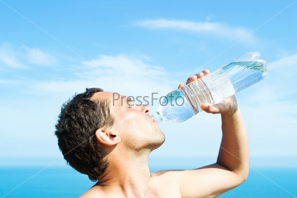 A young man thirsty eagerly drinking water from clear plastic bottles