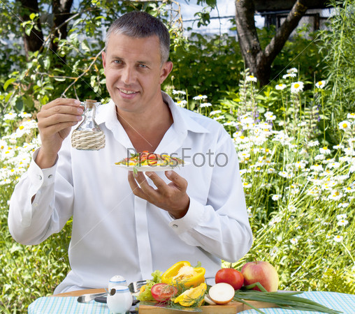 Мужчина-вегетарианец  приготовил салат из свежих аппетитных овощей