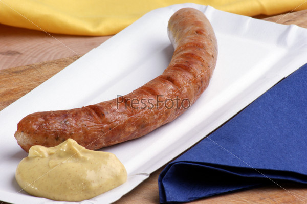 ham sausage with mustard on paper plate