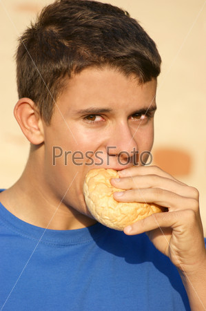 a male teenager eating a bread roll