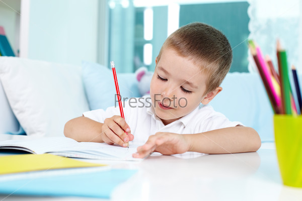 Lovely boy drawing with a pencil, stock photo