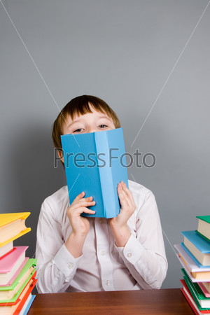Мальчик читает книгу на сером фоне