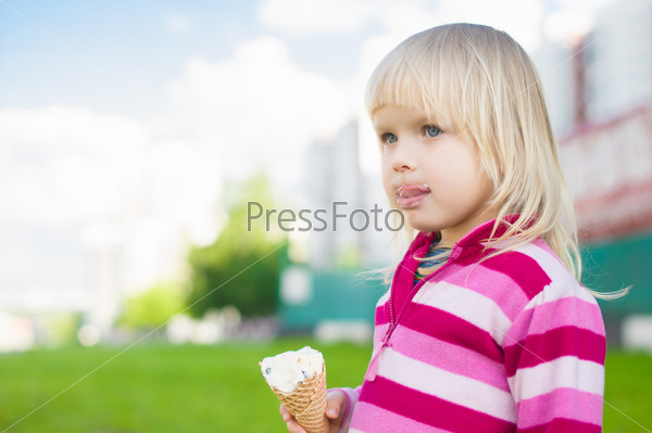 Adorable girl eat ice cream on green grass