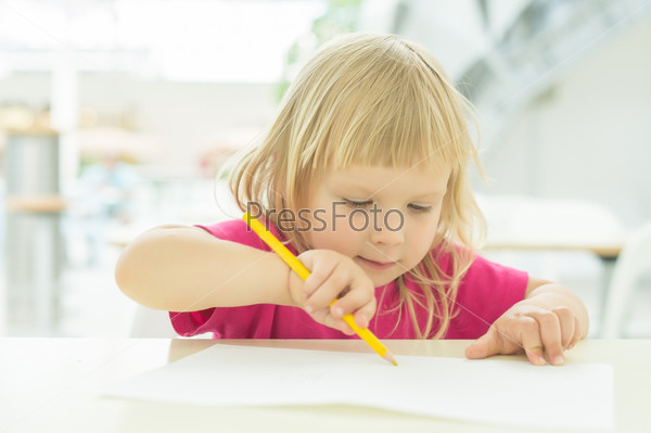 Adorable girl draw with pencil on table on food zone in mall
