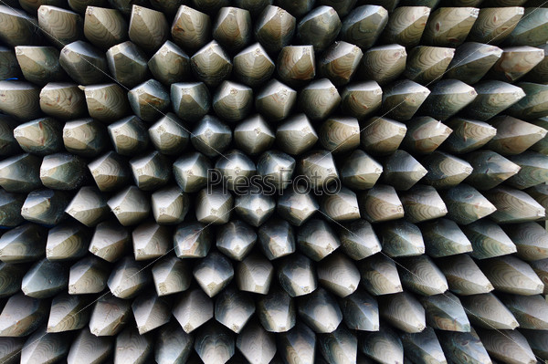 Wooden stakes are pointed and tightly packed in a stack
