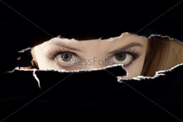 Women\'s eyes spying through a hole close up