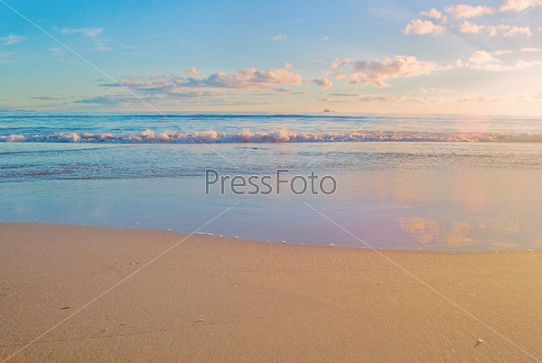 a nice beach scene with gentle waves reaching the sand at sunrise