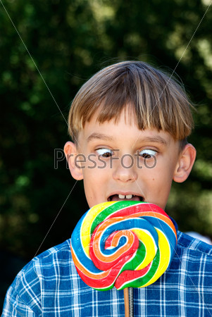 a boy going cross eyed as he looks down at the lollipop that is too big
