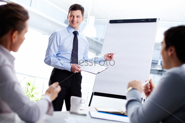 Cheerful office worker pointing at the blank whiteboard making a presentation