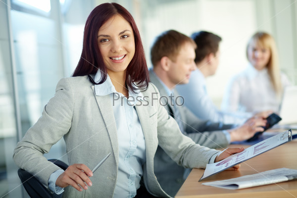 Charming girl holding a folder and looking at camera with a smile, stock photo