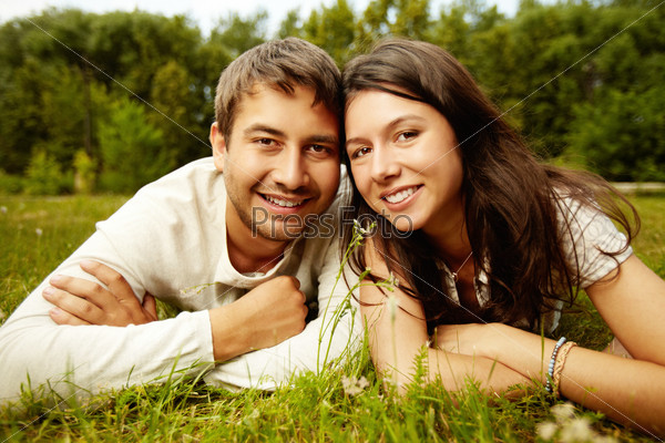Close-up portrait of two happy lovers resting on the grass, stock photo