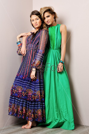 Two beautiful woman posing in a fancy dresses. Studio shooting.