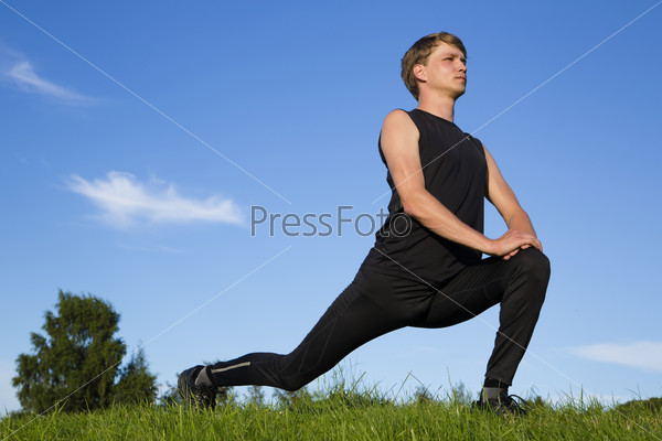 Sportsman making exercise movements to stretch legs, stock photo