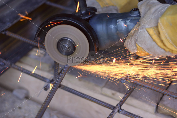 Worker cutting metal with many sharp sparks