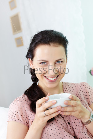 Young girl with cup smiling charmingly at camera