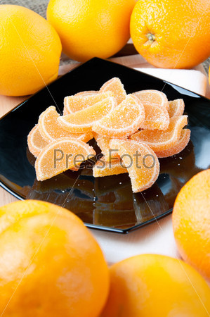 Vertical shot of a glass plate with orange jellies and fresh oranges