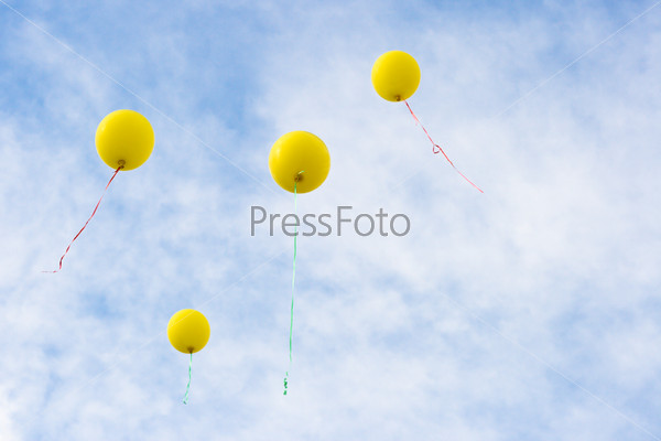 Four yellow baloons rising, stock photo