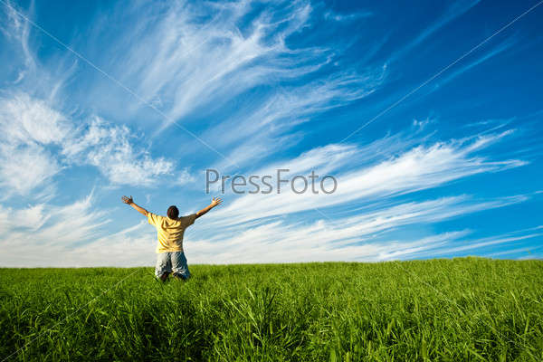 man on knees in the green field  under blue skies