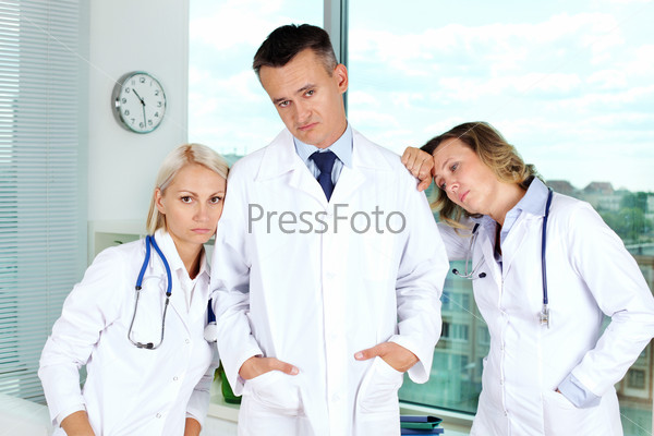Three clinicians in white coats tired after working week
