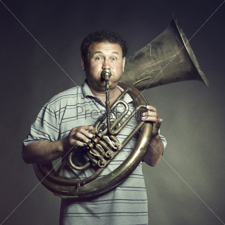 Portrait of an old man close up playing the trumpet. Studio photo