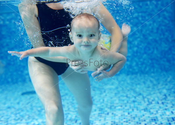 Little boy learning to swim in a swimming pool, mother holding the child, stock photo