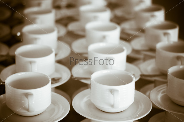 Many rows of pure white cup and saucer designed in vintage retro style. Note: the image contains grain as an element of style.