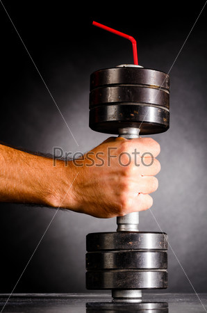 sports nutrition. male hand is holding metal barbell with red straw