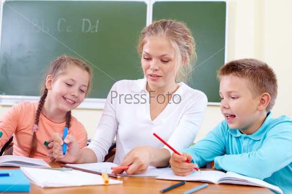 Portrait of two classmates and their teacher drawing with highlighters at lesson, stock photo
