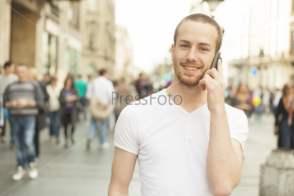Smiling Man talking on mobile phone, city street