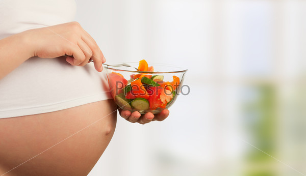 healthy nutrition and pregnancy. pregnant woman\'s belly and vegetable salad