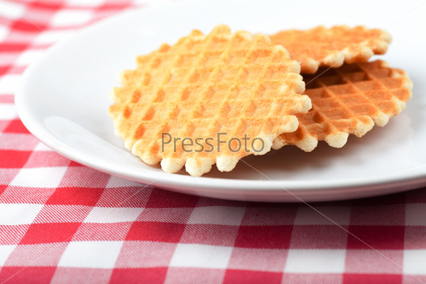 Three golden round waffles on a white plate