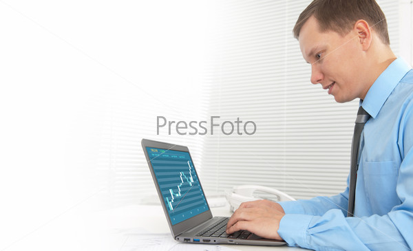 Smiling trader working on his laptop