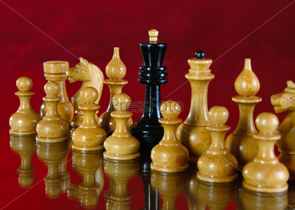 Chess on a red background. Black king for white chess pieces.