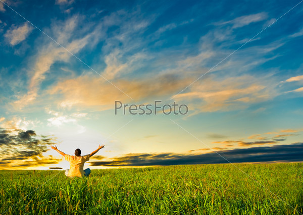 Man sitting in the field under sunset, stock photo