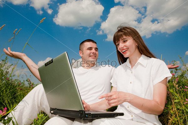Casual happy couple on a laptop computer outdoors