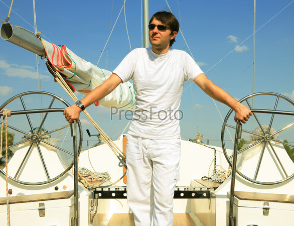 Young man on sailboat desk looks ahead