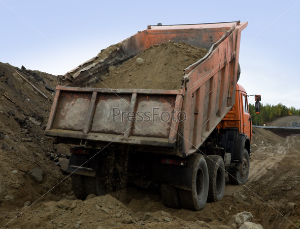 A dump truck is dumping gravel
