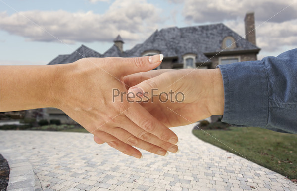 Мужчина и женщина пожимают руки на фоне нового дома