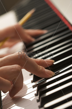 Woman\'s Fingers with Pencil on Digital Piano Keys