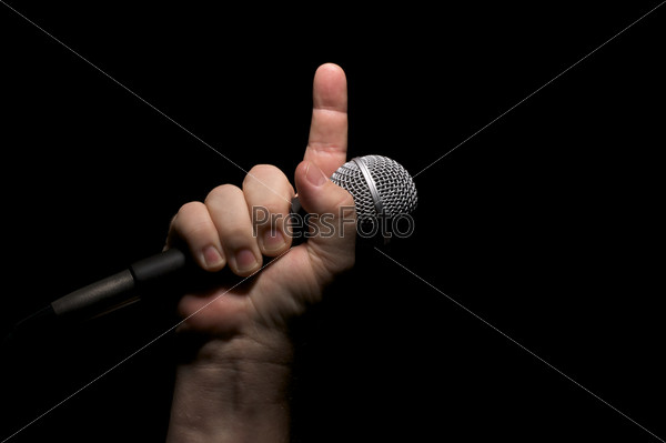 Microphone clinched firmly in male fist with index finger pointing up, stock photo