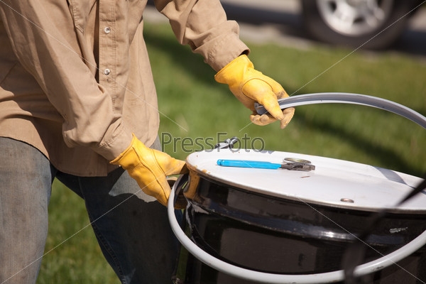 Utility Worker with Leather Gloves Opening or Sealing Oil Drum.