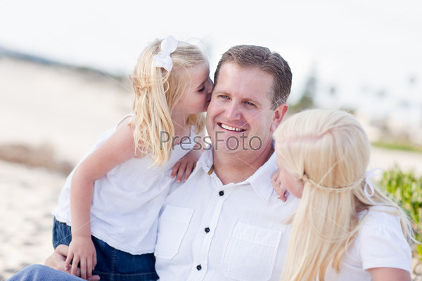 Handsome Dad Getting Kisses from His Cute Daughters at The Beach, stock photo
